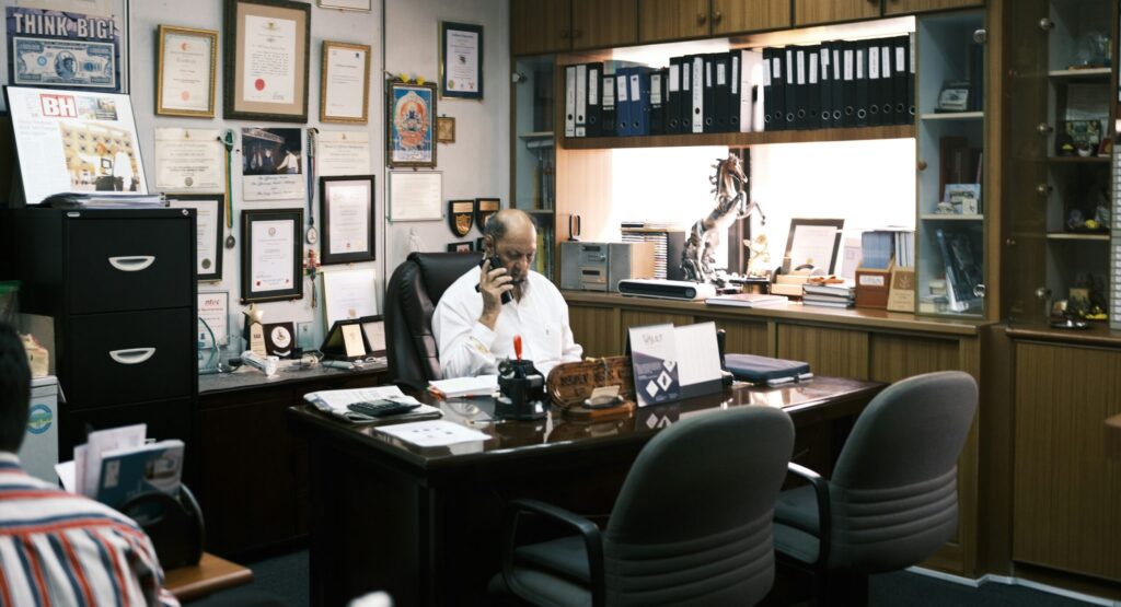 山積みの書類に向かう疲れたビジネスマンの後ろ姿