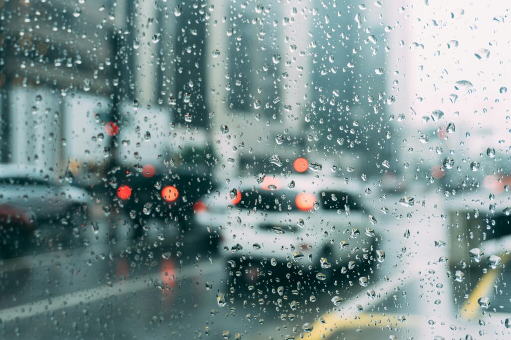 車の窓に映る雨粒、車社会と自転車生活の対比