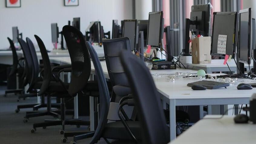 空のオフィス、机の上の鍵とCLOSEDの看板
